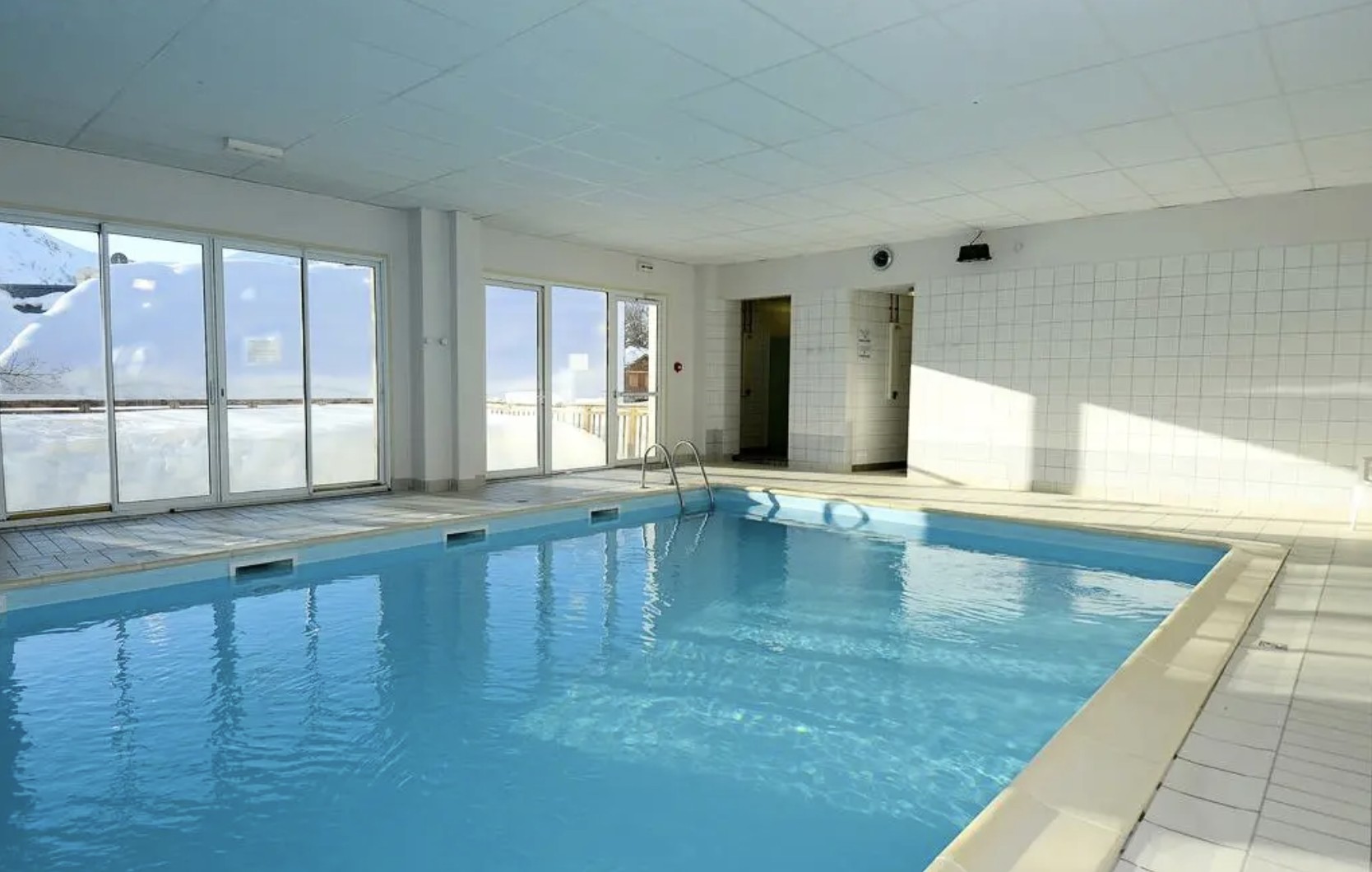 Piscine couverte avec baies vitrées donnant sur la neige