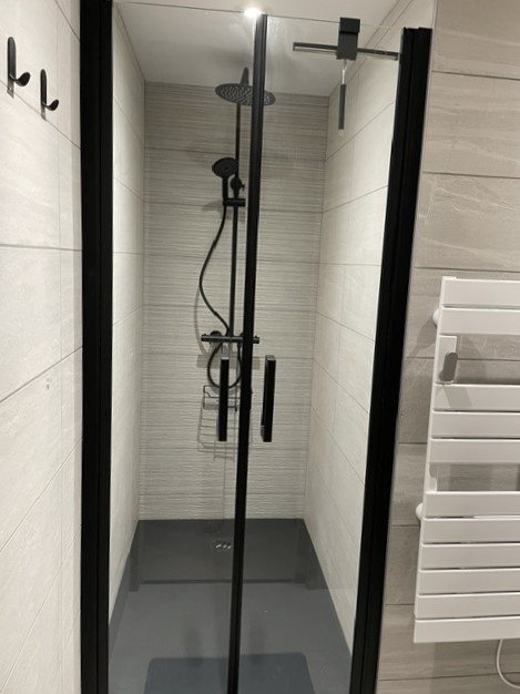Douche à l'italienne avec paroi vitrée noire et sèche-serviettes