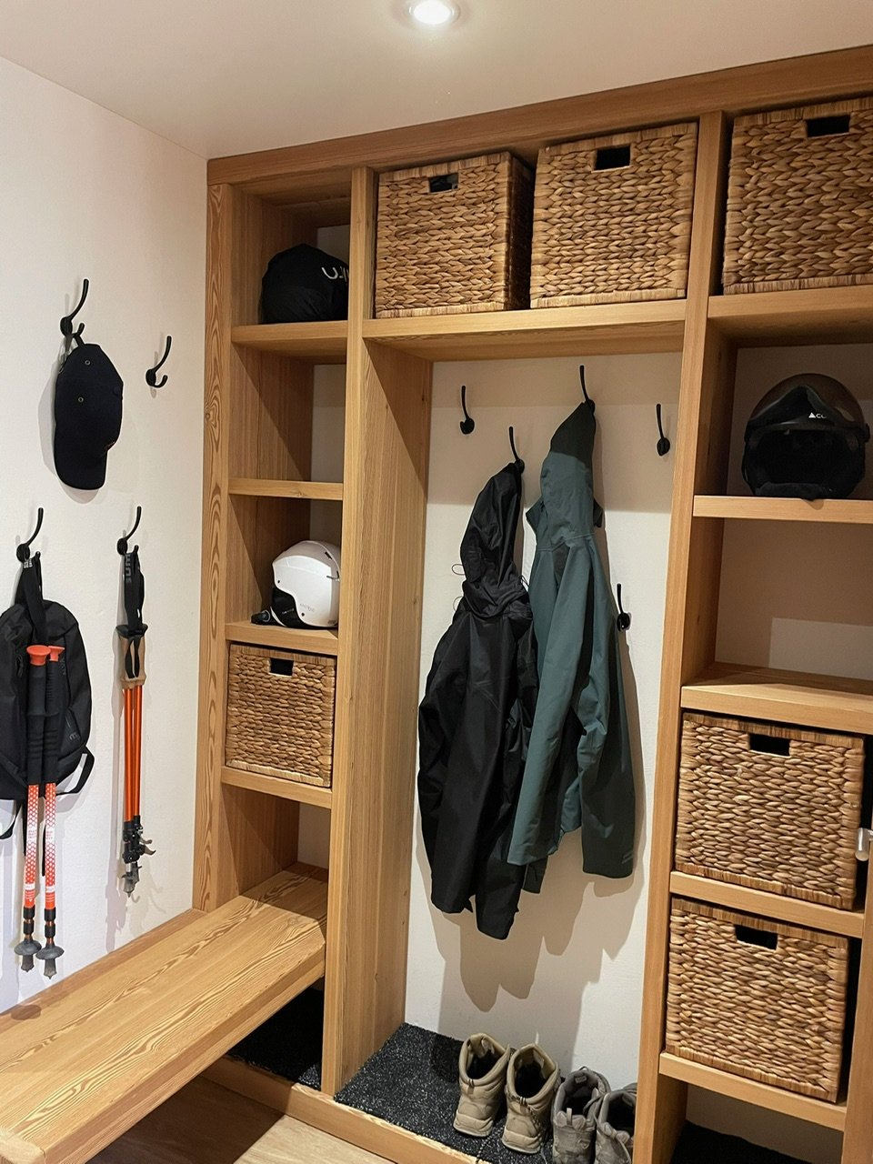 Grand vestiaire d'entrée en bois avec banc, patères et paniers de rangement