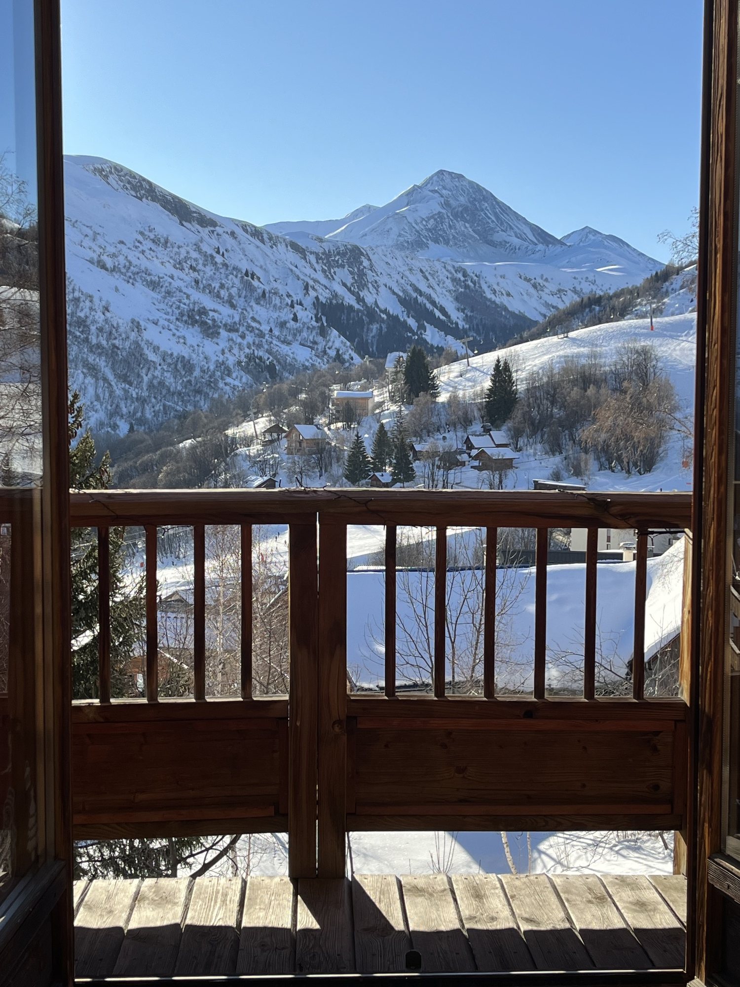Vue sur les montagnes enneigées et les pistes depuis le balcon de l'appartement