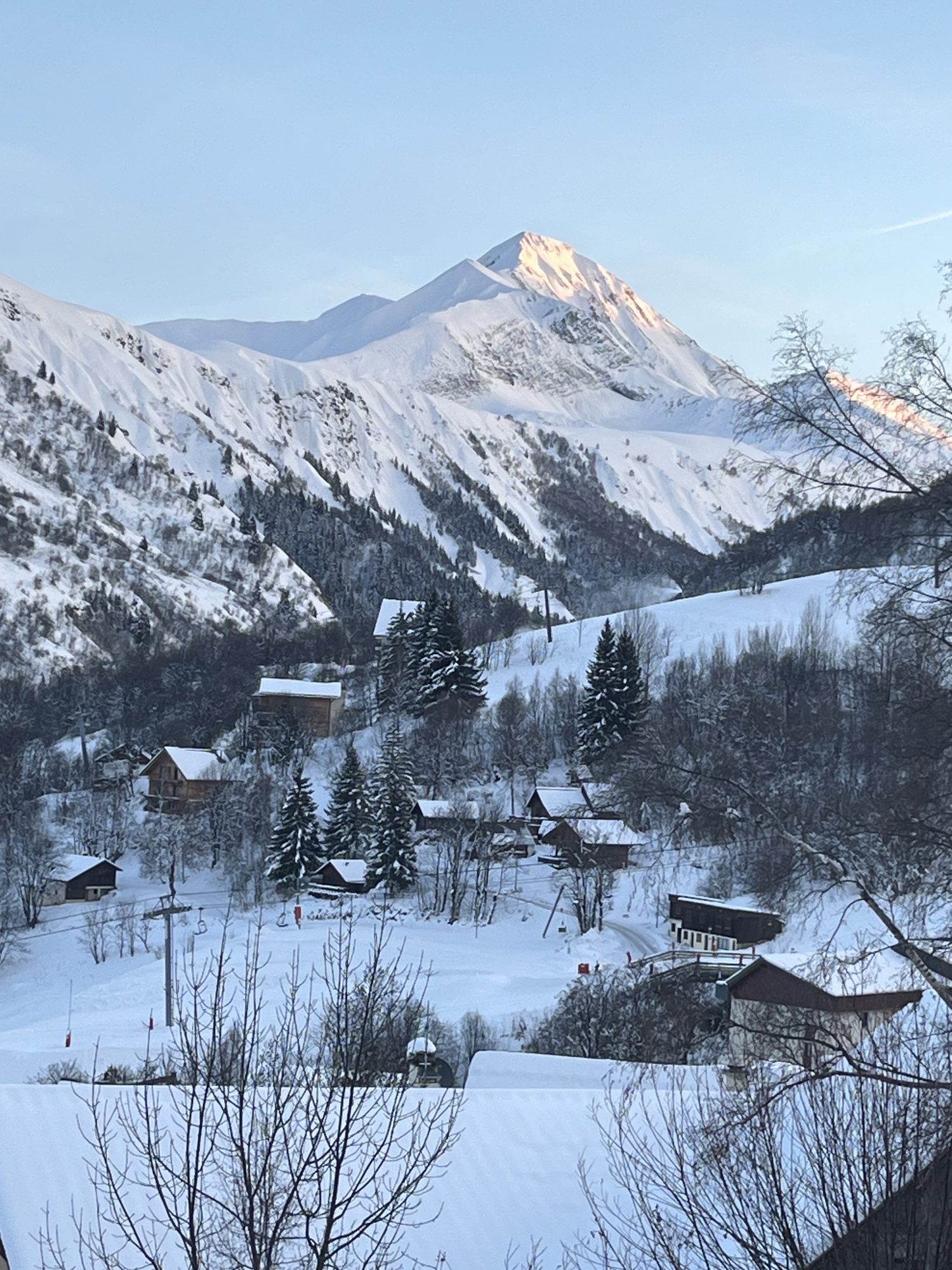 Sommet enneigé éclairé par les dernières lueurs du jour, au-dessus des chalets du village